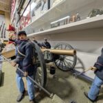 A museum diorama featuring large-scale figures of a Union Army artillery crew from the American Civil War manning a field cannon.