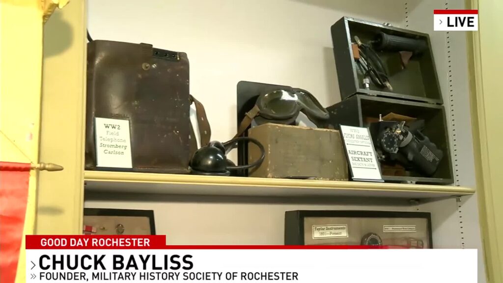 Display of World War II era military equipment including a field telephone, flying goggles, and an aircraft sextant.