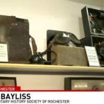 Display of World War II era military equipment including a field telephone, flying goggles, and an aircraft sextant.