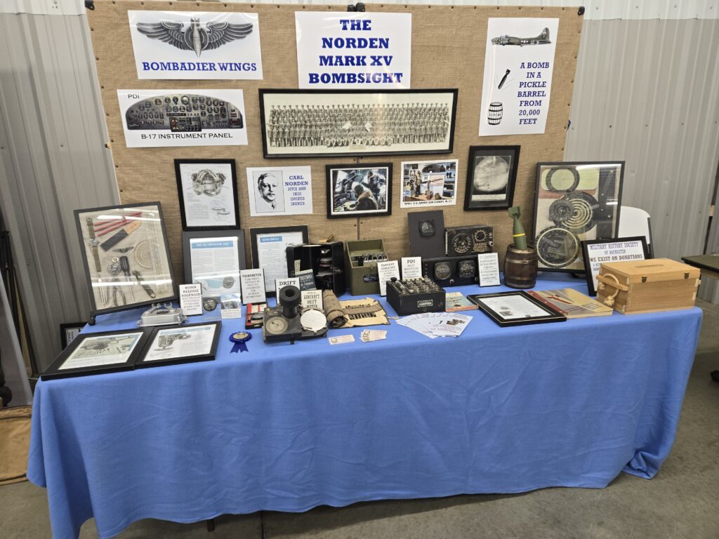 A museum display featuring various artifacts and information about World War II bombing technology, including the Norden Bombsight, B-17 instrument panel, and related devices.